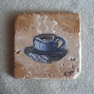 K&ouml;nnte beinhalten: Ein Keramik-Untersetzer mit einem gemalten Bild einer Tasse Kaffee, aus der Dampf aufsteigt.