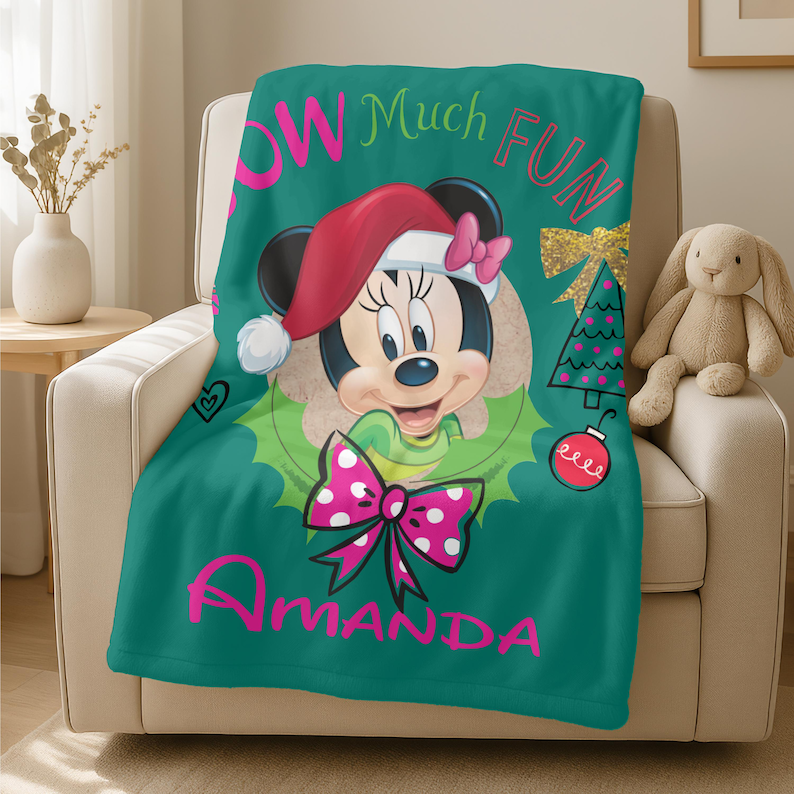 A green blanket with a Minnie Mouse design and the text "Amanda" printed on it, placed on a chair.
