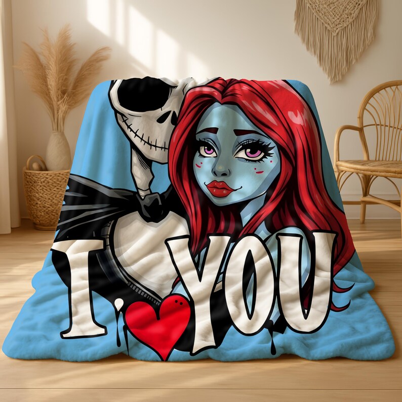a blue blanket with a cartoon illustration of a skeleton and a woman with red hair, along with the text "I YOU" prominently displayed.