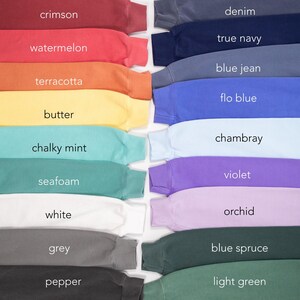 Pode incluir: Uma cole&ccedil;&atilde;o de camisolas de gola redonda em v&aacute;rias cores, incluindo carmesim, melancia e terracota. Outras cores incluem ganga, azul marinho e azul jeans. Cada camisola exibe o seu nome de cor, como "manteiga" e "hortel&atilde; giz".