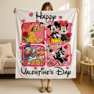 A woman is holding up a white blanket with a collage of Disney characters and the text "Happy Valentine's Day" printed on it.