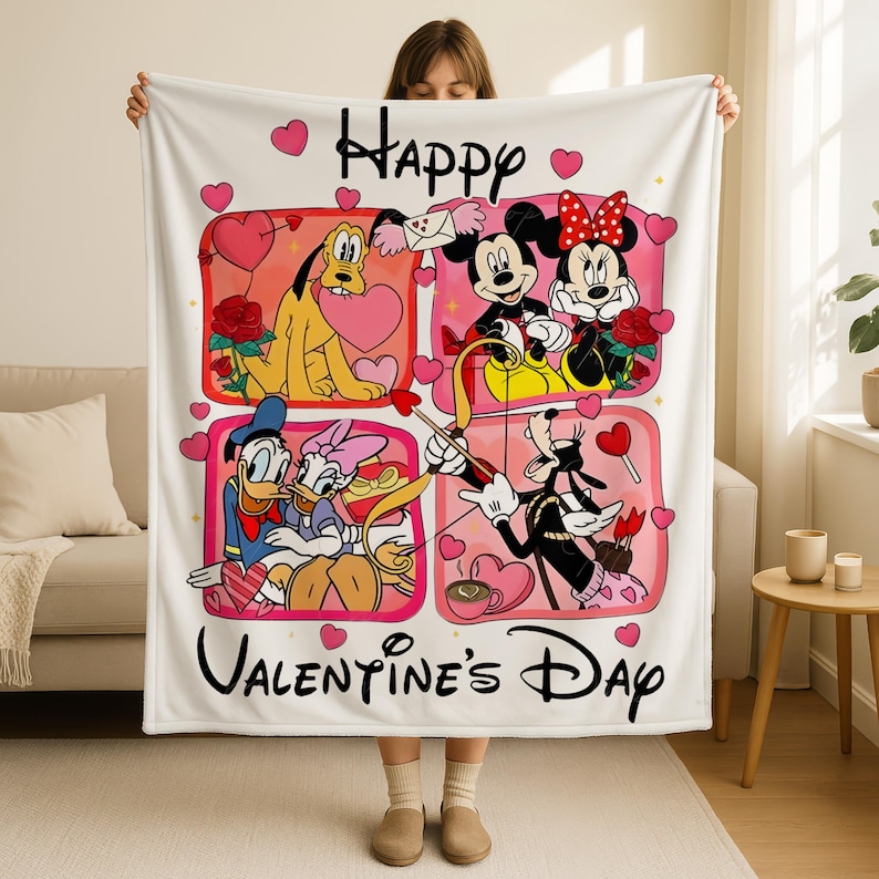 A woman is holding up a white blanket with a collage of Disney characters and the text "Happy Valentine's Day" printed on it.