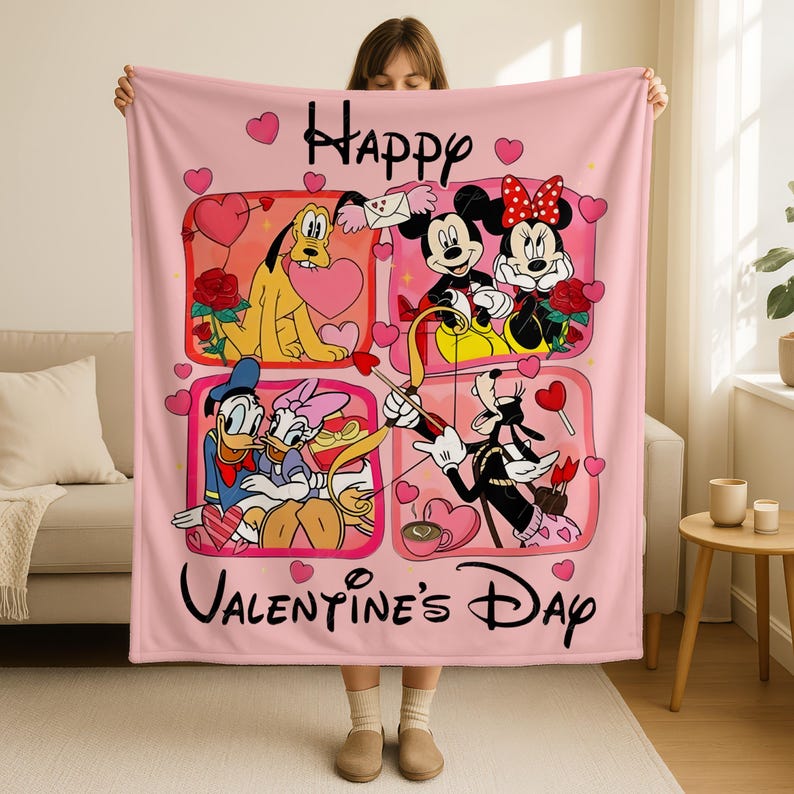 A woman is holding up a pink blanket with a collage of Disney characters and the text "Happy Valentine's Day" printed on it.