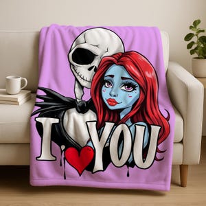 a pink blanket with a graphic design of a skeleton and a woman with red hair. The blanket has the text "I ❤ YOU" written on it.