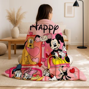 A woman sitting on the floor with a blanket featuring Disney characters.