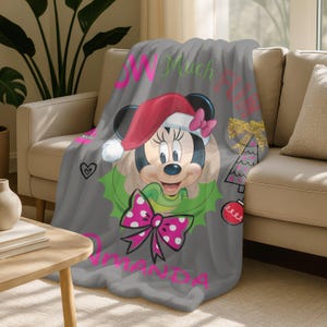 A gray blanket with a Minnie Mouse design and text, including the name "Omanda" and the phrase "W Much Fun".