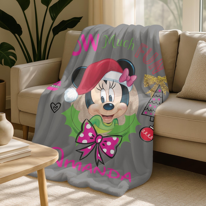 A gray blanket with a Minnie Mouse design and text, including the name "Omanda" and the phrase "W Much Fun".
