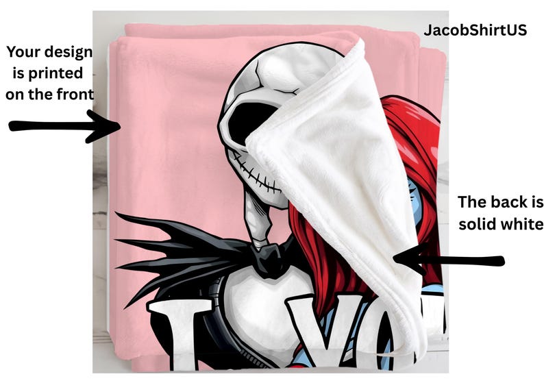 a pink blanket with a cartoon character design, including a skeleton and a red-haired character. The blanket is printed on the front, and the back is solid white.