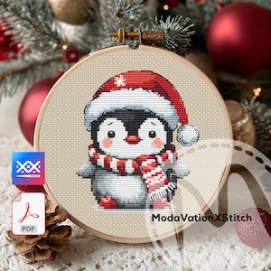 May include: Cross-stitch pattern of a penguin wearing a Santa hat and scarf, set in a wooden embroidery hoop. The penguin is black, white, and gray, with a red and white scarf and hat. The background is a neutral fabric.
