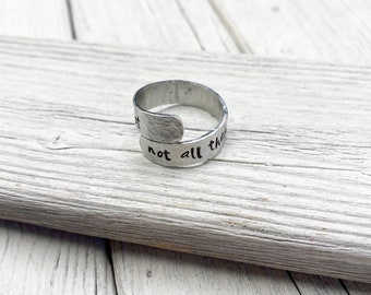 May include: A silver adjustable ring with the words "not all that glitters" engraved on it.