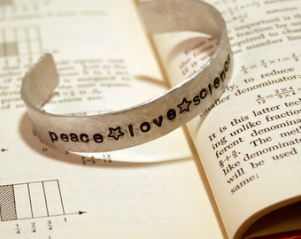 Hand hammered, hand stamped aluminum cuff bracelet: "Peace * Love * Science"