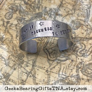 Three quarter inch cuff bracelet with Ursala LeGuin quote: There must be darkness to see the stars. By Geeks Bearing Gifts