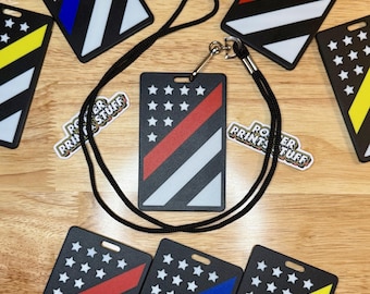 May include: Black badge holders with a diagonal stripe design in red, blue, and yellow, with white stars on a black background. A black lanyard is attached to one badge holder. The text "POTTER PRINTS STUFF" is on stickers.