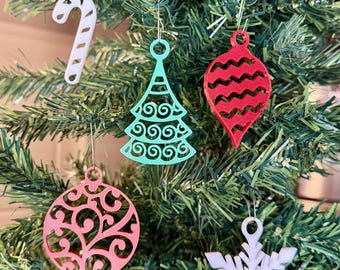 May include: A Christmas tree decorated with various ornaments. The ornaments include a white candy cane, a teal tree, a red teardrop, a pink circular ornament, and a white snowflake. A sign that says "Potter Prints Stuff" is at the top.