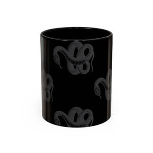 Peut inclure: Un mug cylindrique noir orné d'un motif répétitif de serpents enroulés gris foncé. Les serpents sont représentés dans un style gravé détaillé avec des écailles visibles et des langues fourchues, disposés en un motif continu sur la surface.