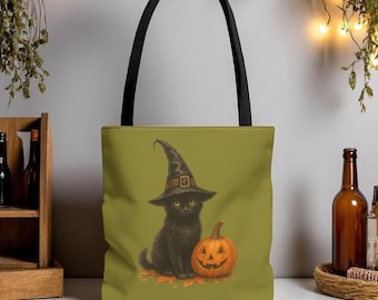 May include: A Halloween-themed tote bag featuring a black cat wearing a witch hat, sitting next to a carved orange pumpkin. The bag has a black handle and a green background. The cat and pumpkin are on a bed of autumn leaves.