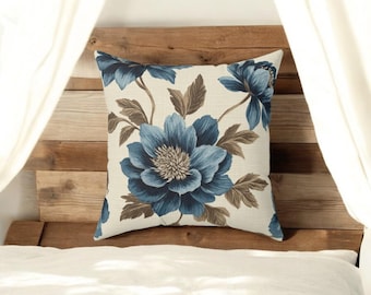 May include: A square throw pillow with a floral design. The pillow features large blue flowers with brown stems and leaves on a white background.