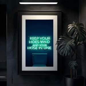 May include: A framed print with a neon green sign that reads "Keep your hoes wild and your hose in line." The sign is in front of a white toilet against a dark blue background.
