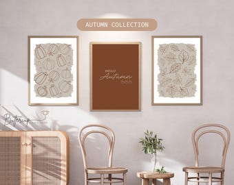 Könnte beinhalten: Drei gerahmte Kunstdrucke mit Herbstmotiven. Einer zeigt Kürbiskonturen, ein anderer sagt "Hello Autumn", und der dritte hat Blätterkonturen. Die Rahmen sind hellbraun und der Hintergrund ist neutral.