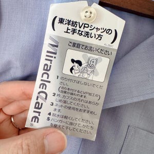 Puede incluir: Camisa azul claro con una etiqueta de cuidado adjunta. La etiqueta presenta texto japon&eacute;s y una ilustraci&oacute;n de una mujer lavando ropa. La etiqueta tambi&eacute;n tiene el texto "Miracle Care".