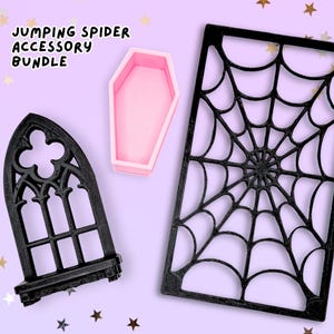 May include: A jumping spider accessory bundle featuring a black gothic-style arched window frame, a small pink coffin-shaped container, and a rectangular black spiderweb frame. The text JUMPING SPIDER ACCESSORY BUNDLE is printed in black.