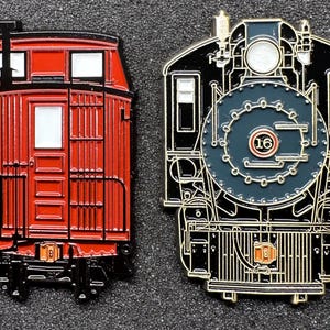 May include: Two enamel pins depicting a red caboose and a black and gold steam locomotive. The caboose has a number "16" on the side. The locomotive has a number "16" on the front.