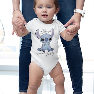 Op de afbeelding: Een witte baby romper met een blauw Stitch-personage uit de Disney-film Lilo & Stitch. De romper heeft de tekst "Ohana means family" erop gedrukt.