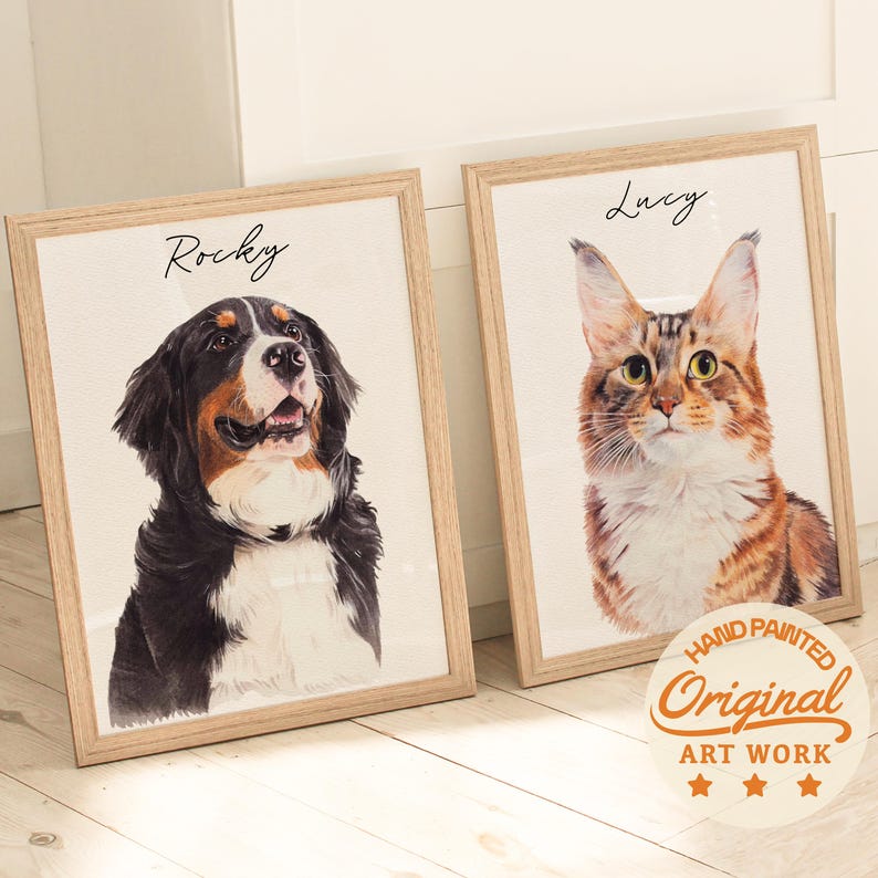 Puede incluir: Dos retratos en acuarela enmarcados de mascotas. Uno presenta un perro de monta&ntilde;a bern&eacute;s llamado Rocky, el otro un gato llamado Lucy. Ambos est&aacute;n en marcos de madera clara. La obra de arte est&aacute; etiquetada como "Hand Painted Original Art Work."