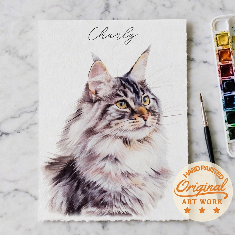 Puede incluir: Pintura a la acuarela de un gato Maine Coon llamado "Charly". La obra presenta un retrato detallado del gato con pelaje gris, marr&oacute;n y blanco, ojos amarillos y un aspecto esponjoso. La pintura est&aacute; firmada e incluye un sello "Hand Painted Original Art Work".