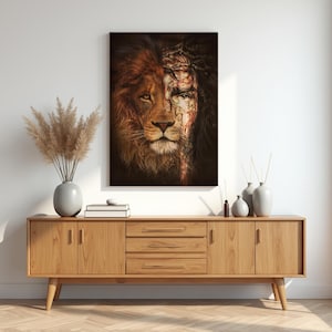 Może przedstawiać: Oprawione dzieło sztuki przedstawiające twarz lwa połączoną z ludzką twarzą, z koroną cierniową. Lewa strona jest złoto-brązowa, a ludzka strona ma koronę cierniową i czerwone akcenty. Grafika jest wyświetlana nad drewnianą szafką.