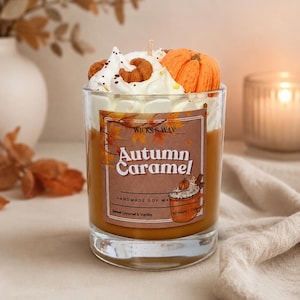 May include: A clear glass candle filled with caramel-coloured wax, topped with white whipped wax and a small orange pumpkin decoration. The label reads Wicks & Wax Autumn Caramel, Handmade Soy Wax Candle, Sweet Caramel & Vanilla, 40 hours | 250g.