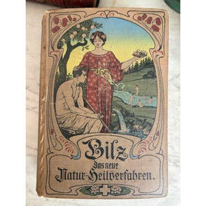 Puede incluir: Portada de libro antiguo con una ilustración colorida. Muestra a una mujer con un vestido rojo sosteniendo fruta, un hombre y un paisaje con figuras bañándose. El título "Bilz" es prominente, con texto alemán debajo. La portada tiene un estilo Art Nouveau.