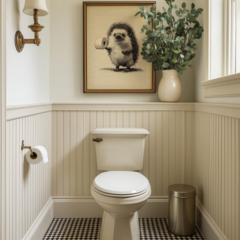 A whimsical hedgehog print with funny bathroom wall art humor is elegantly framed above a classic toilet, complemented by vintage lighting and a chic vase with greenery.