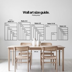 A minimalist dining room with light wood furniture showcases a vintage wall art size guide above, accented by elegant ceramic vases for a touch of cottagecore decor.