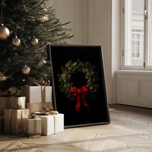 In a sumptuous dark wood frame, a festive wreath painting with a red bow exudes cozy holiday charm beside an elegantly decorated Christmas tree and stylishly wrapped gifts, capturing timeless winter decor and old money vibes.