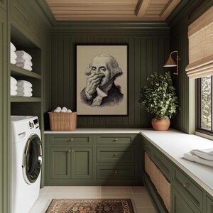 A whimsical vintage sketch of George Washington humorously holding his nose is elegantly framed on an olive green paneled wall, adding a touch of funny bathroom art to this stylish space. Natural light spills onto the woven basket and lush plant, creating a cozy ambiance.