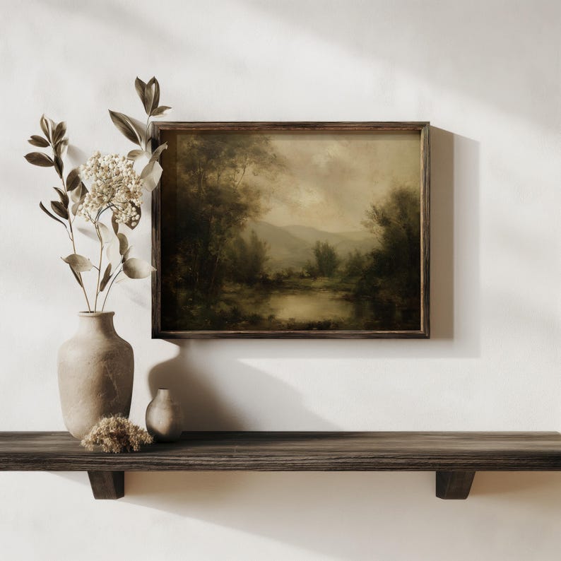 A moody vintage oil painting in a rustic wooden frame sits above a dark wood shelf, accented by dried hydrangeas in ceramic vases, evoking a serene farmhouse decor.