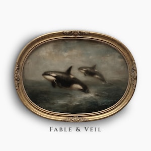 Puede incluir: Pintura enmarcada ovalada con dos orcas emergiendo del agua. La obra de arte utiliza tonos apagados de gris, azul y blanco, con un marco dorado ornamentado. El texto "FABLE & VEIL" está impreso en la parte inferior.