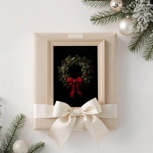 A beautifully wrapped beige frame showcases a festive wreath with a red bow, surrounded by evergreen branches and silver ornaments, evoking a cozy holiday atmosphere perfect for dark academia decor.