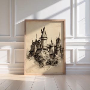 A vintage sketch of a castle, reminiscent of a wizard school, rests elegantly in a minimalist wooden frame against a sunlit white paneled wall. The artwork exudes a moody art vibe, perfect for wizarding decor enthusiasts.