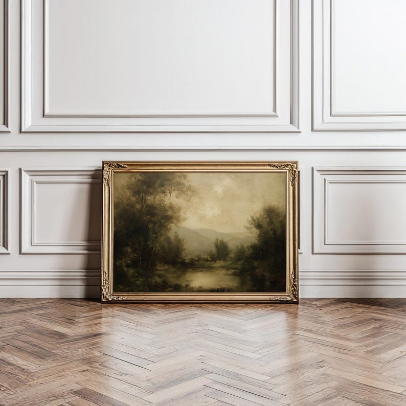 A moody vintage oil painting framed in ornate gold leans elegantly against a paneled wall, casting an antique charm over the herringbone floor with its serene dark academia landscape.
