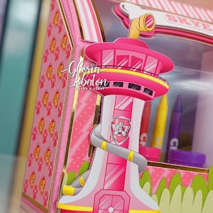 Pode incluir: Uma caixa de cart&atilde;o rosa e amarela com uma janela de pl&aacute;stico transparente. A caixa apresenta uma torre rosa e amarela com um logotipo de pata cinza e a palavra "Skye" no topo. A caixa &eacute; decorada com um padr&atilde;o de listras rosa e brancas e um padr&atilde;o de pegadas.