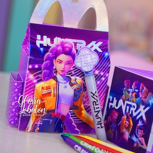May include: A purple party box with a handle, displaying a graphic of a woman with purple hair and the text "HUNTRAX." A light-up wand and a small booklet with the same design are also present, alongside colourful crayons.