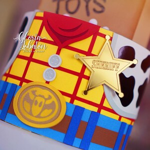 May include: A close-up of a decorative item resembling a sheriff's vest from the movie Toy Story. The item features a yellow background with a red plaid pattern, a gold sheriff's badge, and a brown and white cowhide pattern.