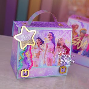 Puede incluir: Una caja decorativa con asa, con temática K-Pop. La caja está adornada con una etiqueta en forma de estrella e ilustraciones de figuras animadas. La combinación de colores incluye acentos morados, rosas y dorados, con el texto "K-POP DEMON HUNTERS".
