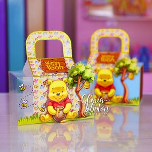 Può includere: Due scatole regalo a tema Winnie the Pooh. Ogni scatola presenta il personaggio giallo di Winnie the Pooh che tiene un vasetto di miele, con un albero e un alveare. Le scatole hanno un fronte trasparente e una parte superiore a fantasia con una maniglia.
