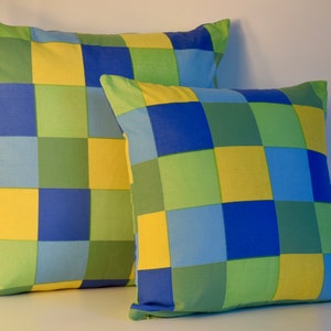 May include: Two square throw pillows with a checkered pattern in shades of blue, green, and yellow.
