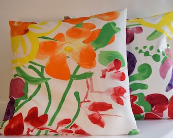 May include: Two white pillowcases with a floral pattern. The pattern features large orange, yellow, red, and green flowers on a white background.
