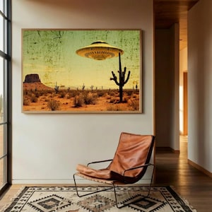 May include: A framed art print depicts a desert landscape with a vintage aesthetic. A yellow UFO hovers above a cactus. The scene includes a mesa, cacti, and desert vegetation under a yellow and green sky. A leather chair and patterned rug are in the foreground.