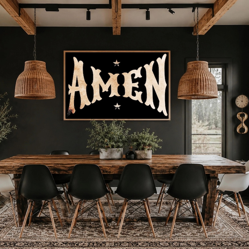 May include: A large framed sign with the word "AMEN" in a vintage font, set against a black background with two small stars. The sign hangs above a wooden dining table with black chairs, creating a rustic and spiritual aesthetic.
